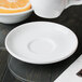 A white porcelain tea saucer with a slightly raised center, designed for holding a teacup.