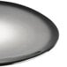 A round, dark gray porcelain plate with a smooth, organic shape.