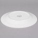 A white porcelain plate with a wide rim, shown upside down.