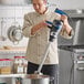 A chef using a Waring WSB650X Big Stik EvolutionX 18-inch electric variable-speed heavy-duty immersion blender in a commercial kitchen.