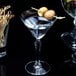 A clear 6 oz. martini glass filled with a drink and garnished with two green olives on a cocktail pick.