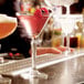 A clear 6 oz. martini glass filled with a red cocktail and garnished with berries.