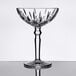 A clear, faceted cocktail glass with a decorative stem and a wide bowl.