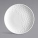 A white porcelain round coupe plate with a textured geometric pattern on one side.