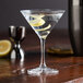 A clear Spiegelau Perfect Serve 5.5 oz. martini glass filled with a cocktail and garnished with a lemon twist.