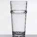 A clear, stackable 16 oz. plastic cooler glass with a textured surface and a pronounced ring near the top.