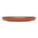 A round, clay-colored satin matte porcelain flat coupe plate.