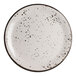 A round white coupe plate with black speckled pattern and a dark rim.