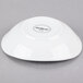A small, bright white oval porcelain bowl shown upside down.