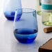 A blue-tinted stemless white wine glass with a rounded shape.