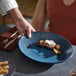 A blue oval terracotta platter with a small gourmet food serving on it.