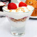 A clear Libbey Series V 7.6 oz. martini glass filled with layers of yogurt, granola, and strawberries.
