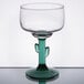 A clear margarita glass with a green cactus-shaped stem and base.