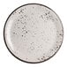 A round white plate with black speckled pattern and a dark rim.