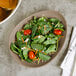 A sand satin matte organic porcelain coupe plate holding a fresh spinach salad with cheese and vegetables.