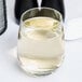 A clear, stemless white wine glass with a capacity of 15.25 ounces, partially filled with white wine.
