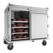 A stainless steel meal delivery cart with multiple shelves holding trays and bowls, designed for transporting food in institutional settings.