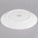 A white porcelain coupe plate shown upside down on a gray background.