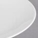A white round porcelain coupe plate with a subtle textured rim.