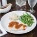 A white porcelain coupe plate holding sliced turkey with gravy, mashed potatoes, and green beans.