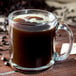 A clear glass mug filled with black coffee.