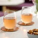 A pair of Libbey 9 oz. stemless wine glasses filled with rosÃ© wine, placed on round coasters on a table.