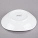A white oval porcelain bowl shown upside down on a gray surface.