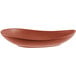 A clay-colored, oval-shaped porcelain coupe plate with a satin matte finish.
