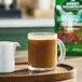 A clear glass mug filled with coffee sits on a wooden tray next to a small white creamer, with a bag of Green Mountain Coffee Roasters Costa Rica Paraiso Whole Bean Coffee in the background.