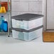 A pair of clear plastic storage totes with flat gray latching lids, stacked on the floor.