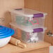 A clear plastic storage box with a purple latch handle lid, used for organizing items.