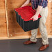 A black industrial storage tote with a red hinged lid being carried by a person.