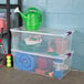 A set of two large clear plastic storage boxes with white lids and purple handles, filled with various household and gardening items.