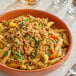 A bowl of penne pasta topped with MorningStar Farms plant-based vegan Italian sausage style crumbles and garnished with herbs.