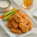 A plate of MorningStar Farms plant-based vegan buffalo wings served with celery, carrot sticks, and a side of dipping sauce.