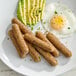 A plate of plant-based vegetarian breakfast sausage links served with sliced avocado and a fried egg.