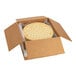 A par-baked pizza crust in a cardboard shipping box with open flaps.
