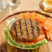 A plant-based vegan garden veggie burger patty served on a bed of lettuce with sliced cucumbers, tomato, and a side of crinkle-cut carrots.