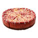 A pre-cut red velvet ricotta cheesecake with a chocolate crust and white icing drizzle.