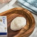 A bar of Dove cream beauty soap with some lather, placed on a wooden soap dish.