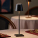A black cordless rechargeable table lamp with a slim design, placed on a dining table.