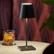 A small black cordless rechargeable table lamp with a square base and conical shade.