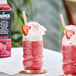 A glass of strawberry frozen beverage topped with whipped cream, a strawberry slice, and a decorative paper umbrella.