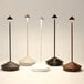 A set of five modern, cordless rechargeable table lamps in various colors with slim stems and conical tops.