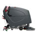 A large, industrial floor scrubber machine with a grey body and red accents, designed for commercial cleaning.