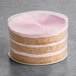 A round, layered vegan strawberry naked cake with pink frosting between the layers and on top.