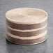 A round, layered vegan chocolate cake with visible chocolate and cream layers, wrapped in a clear acetate collar.