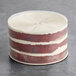 A round vegan red velvet naked cake with visible layers of red cake and white frosting.