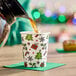 An 8 oz. paper hot cup with a Christmas-themed print featuring trees, presents, holly, and candy canes.