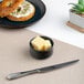 A small black round embossed porcelain ramekin filled with butter cubes.